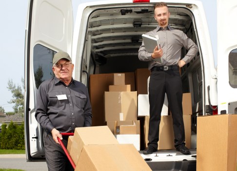 Removal company team preparing a move in Brockley street with boxes and van